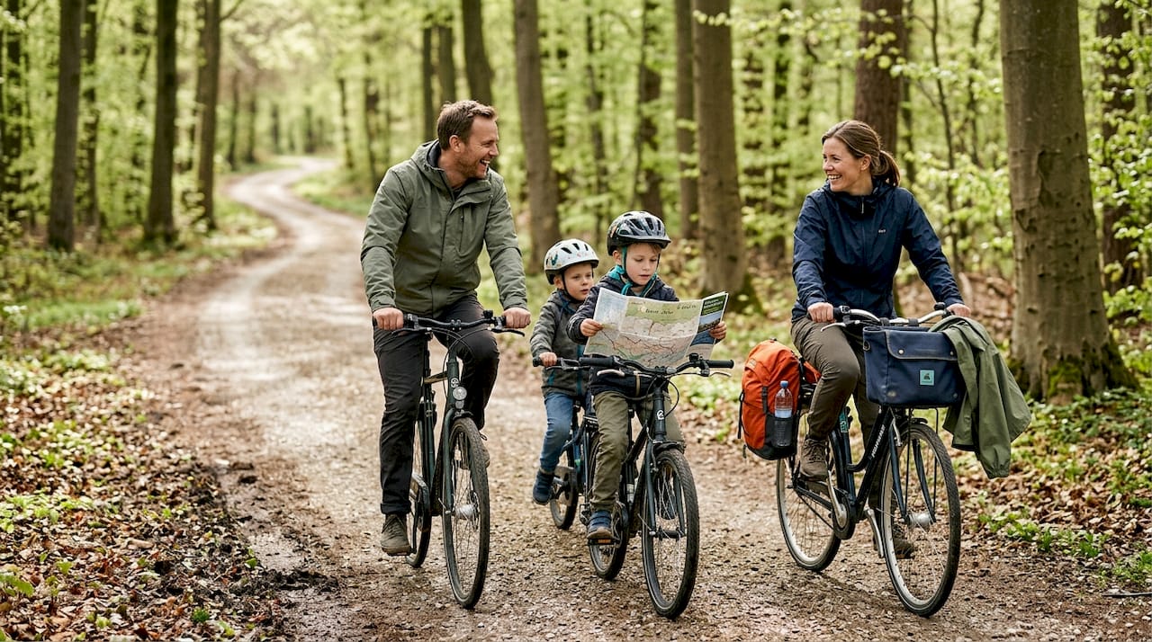 En familie tager på cykeltur gennem den lyse bøgeskov