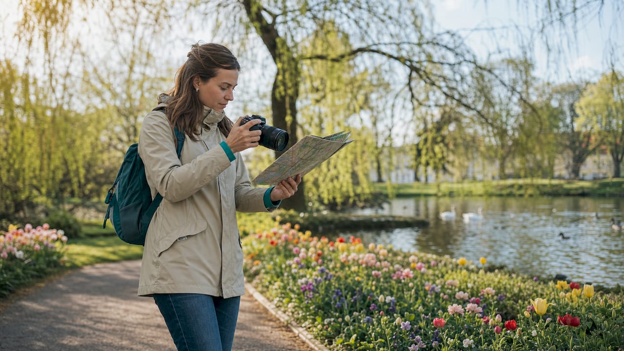 A tourist is standing in the middle of the city and trying to find the way by studying his map.