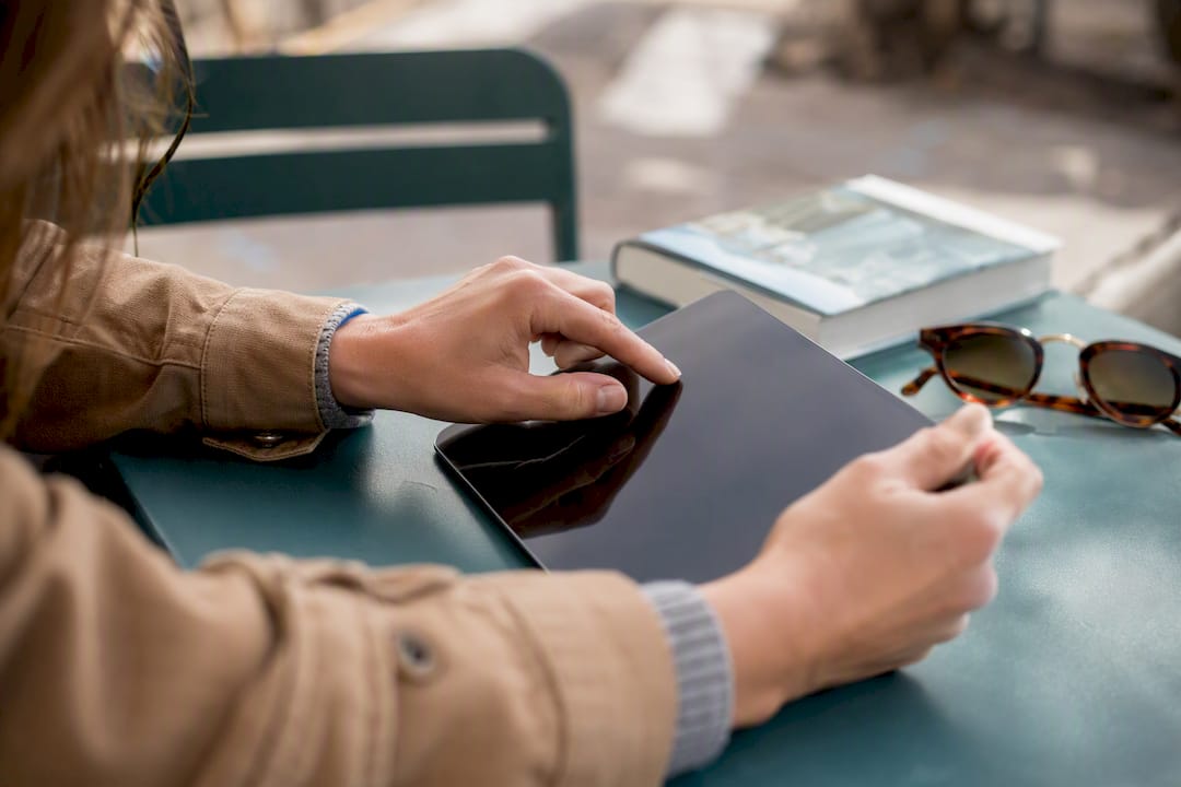 Hände, die eine Reise planen, indem sie eine Karte auf einem Tablet verwenden