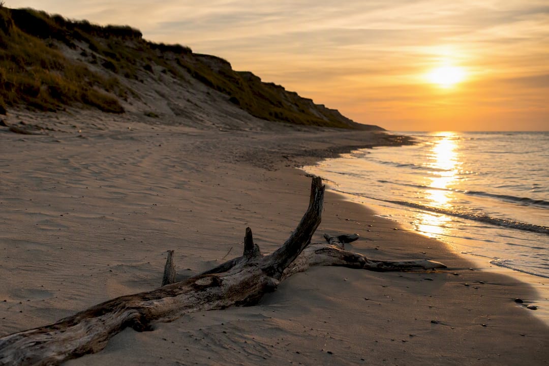 Dänischer Strand bei Sonnenuntergang mit Dünen und ruhigem Meer
