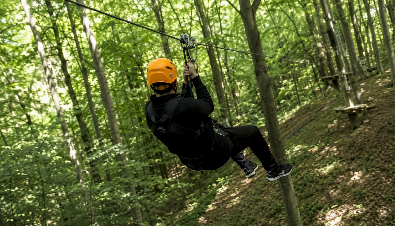 En person suser hen over svævebanen midt i Kragerups klatrepark.