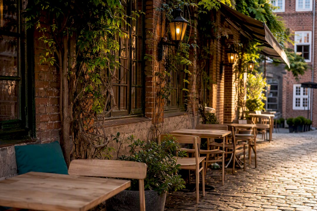 Der gepflasterte Innenhof vor dem Café in Roskilde liegt leer in der Abendsonne.