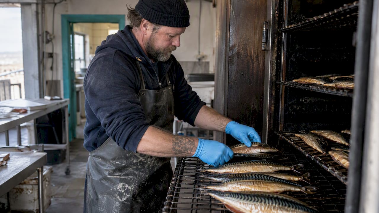 En medarbejder lægger fisk på riste i røgeriet